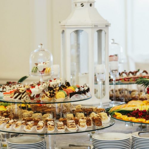 Large glass trays with sweets stand on the white buffet