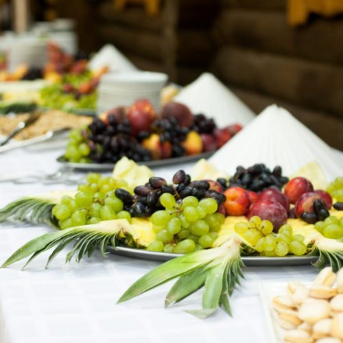 Large trays with fruits stand on the white buffet